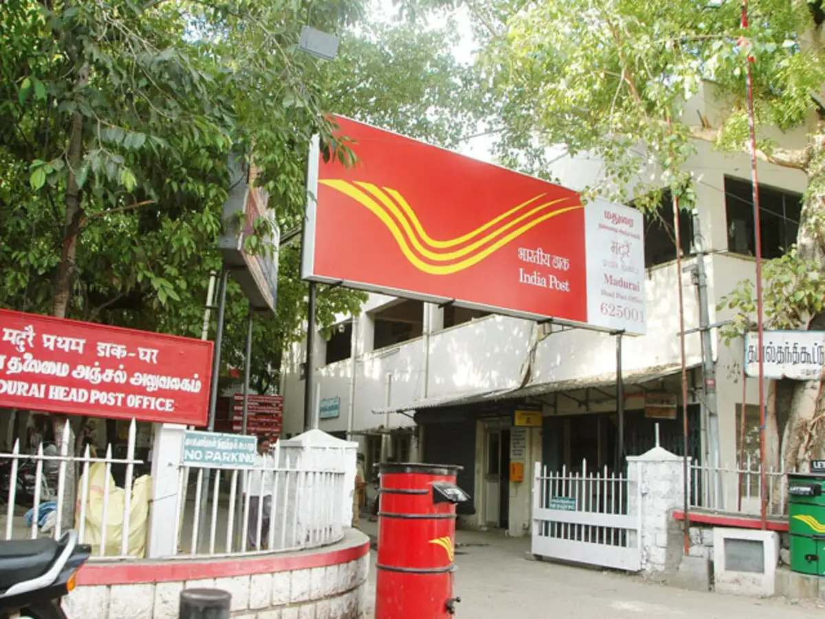 Senior citizen filling out Post Office SCSS application form at a post office counter