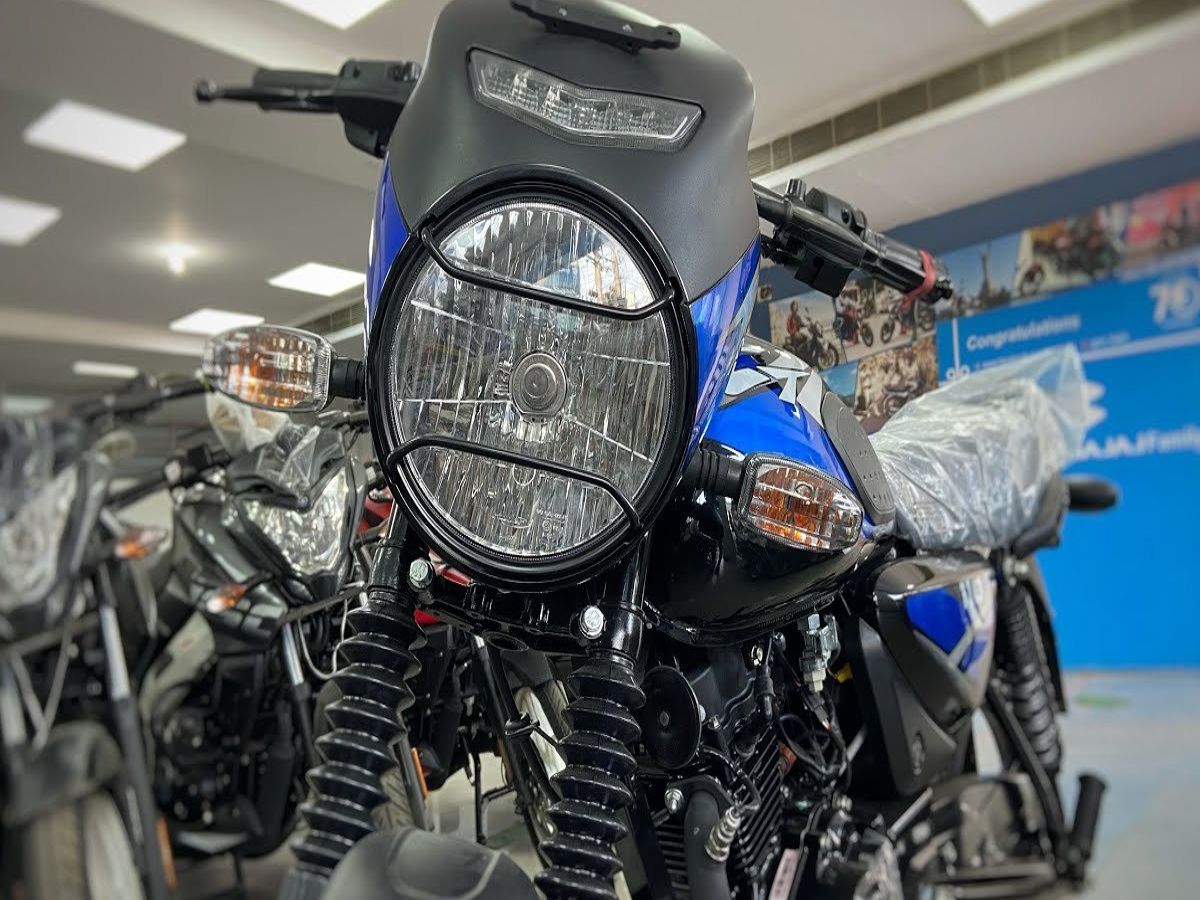 Side view of Bajaj CT 100 navigating through city traffic, emphasizing its lightweight and agile performance.