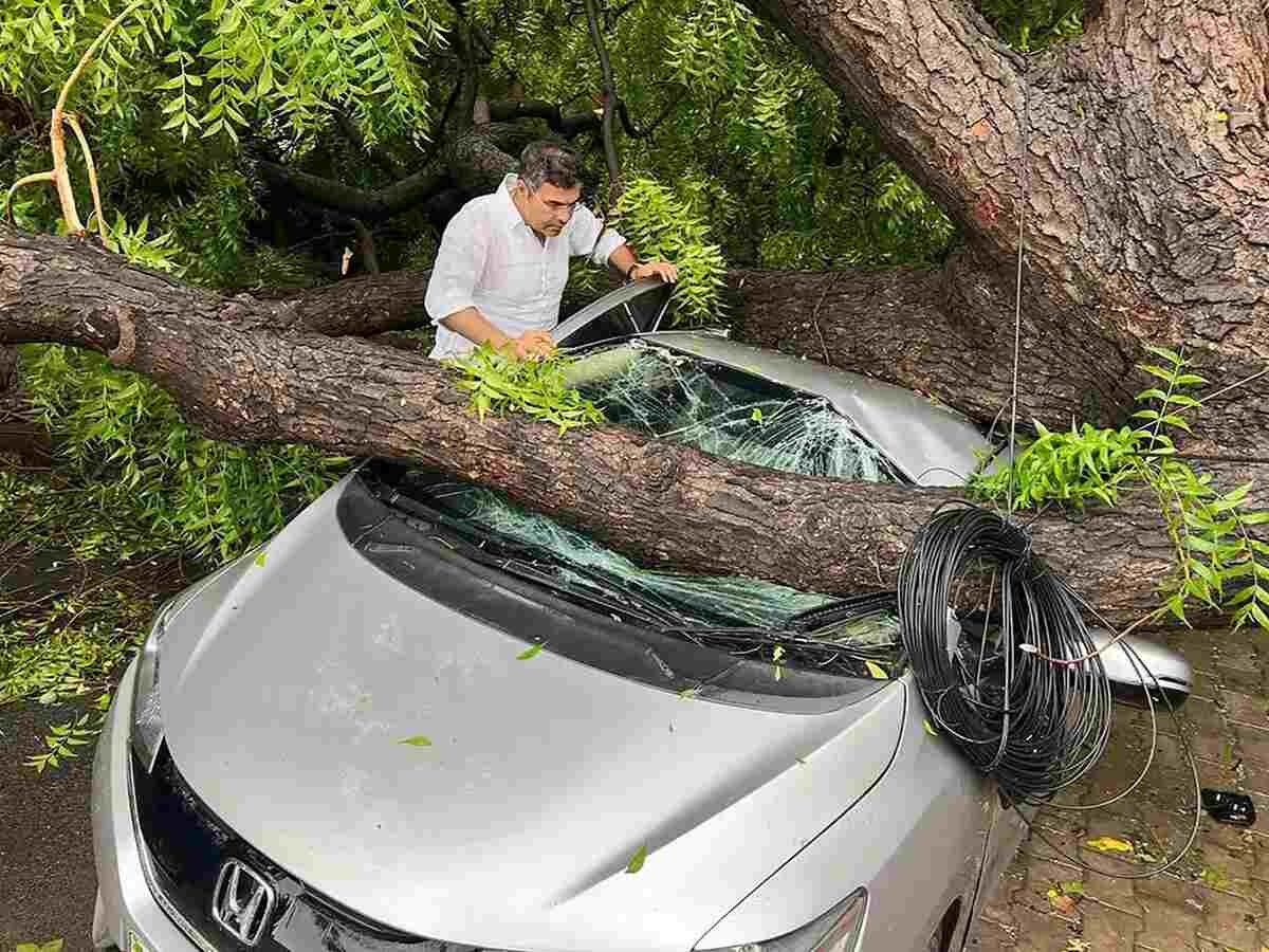 Insurance claim process for vehicle damage – Image depicting a person filing an insurance claim with documents and photos of car damage from monsoon rains.