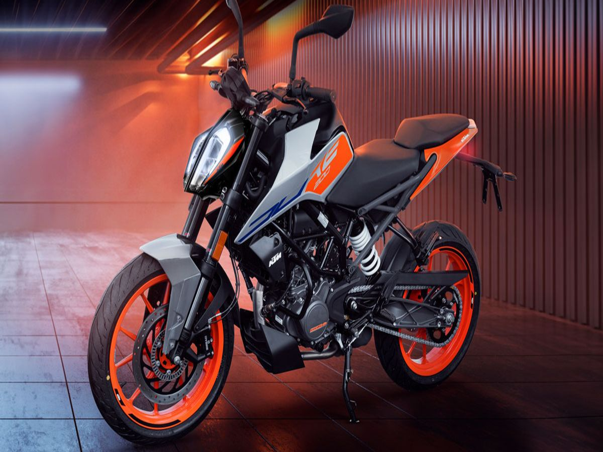 KTM 160 Duke bike in vibrant orange color on a city road, showcasing its sporty design.