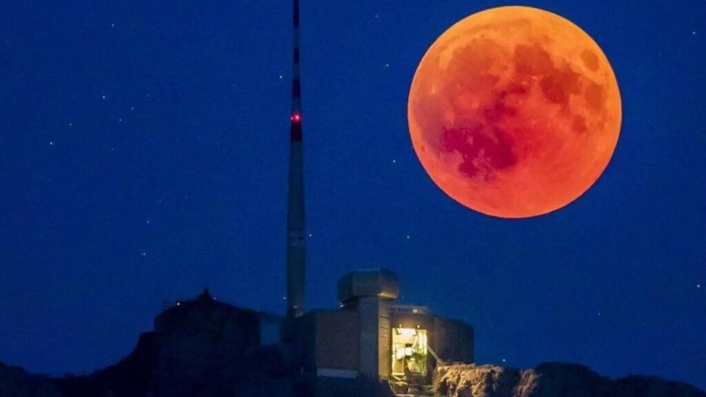 A breathtaking view of the 2025 lunar eclipse with the moon glowing red against a starry sky.