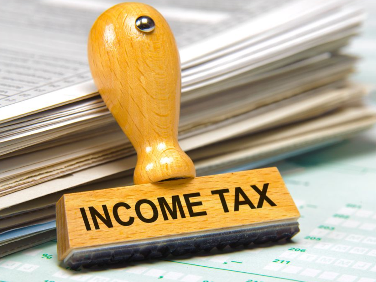 Person filling out an ITR form with financial documents on a desk