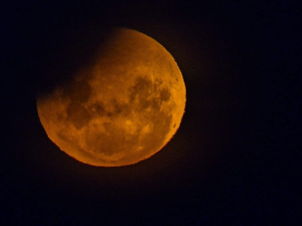 A breathtaking view of the 2025 lunar eclipse with the moon glowing red against a starry sky.