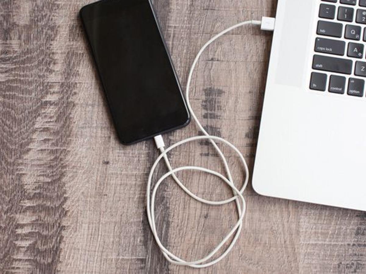 Close-up of a laptop USB port with a charging cable, emphasizing cybersecurity risks.